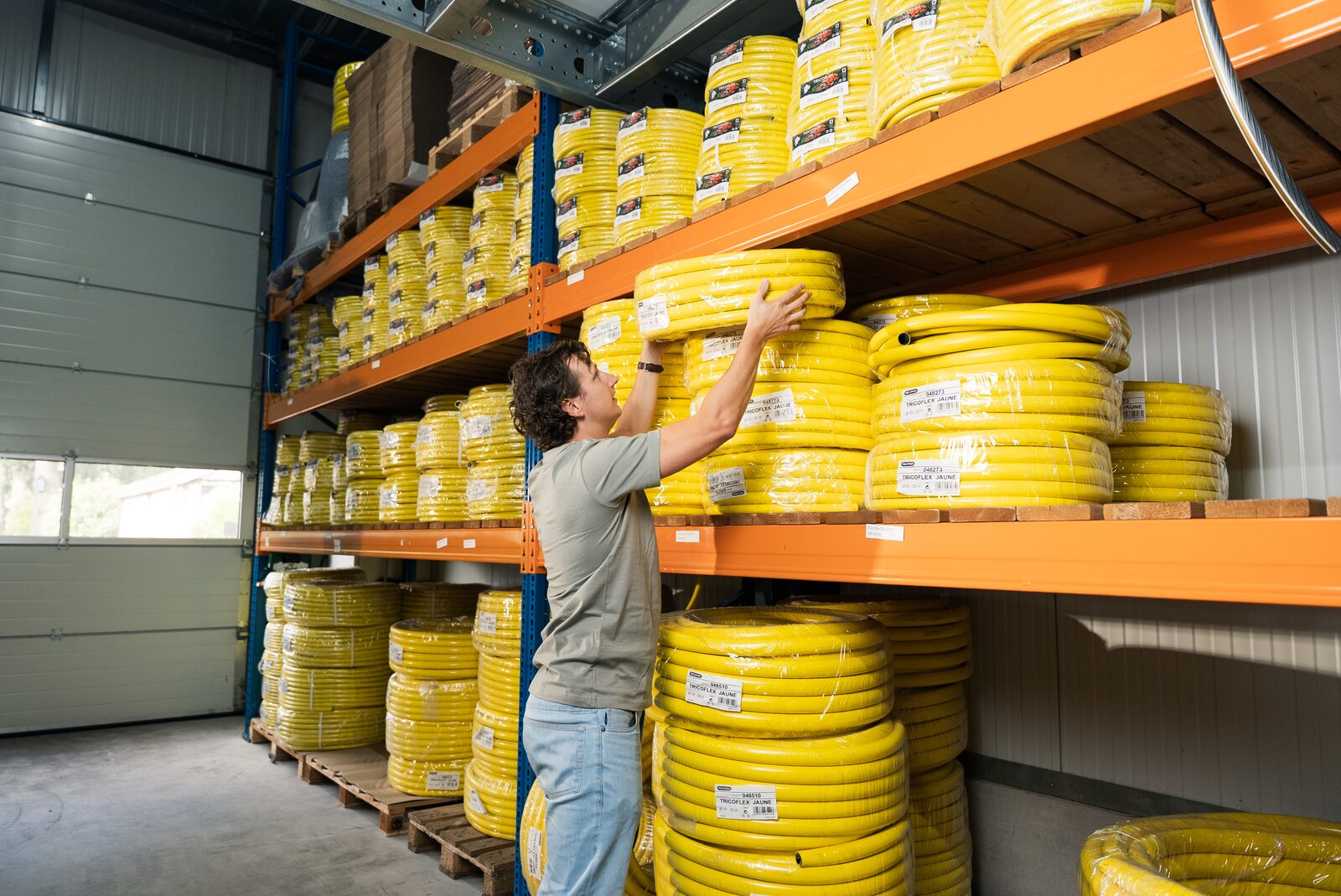 Medewerker pakt een gele waterslang uit het magazijn van Slangenboer