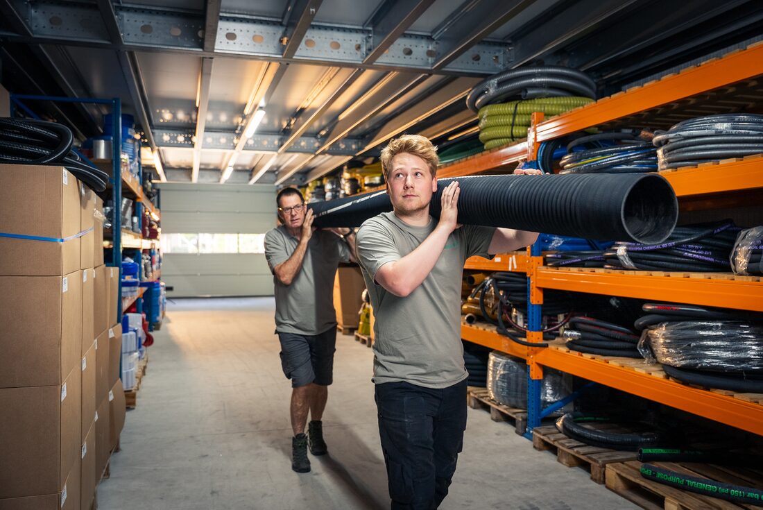 Twee medewerkers van Slangenboer dragen samen een slang door het magazijn
